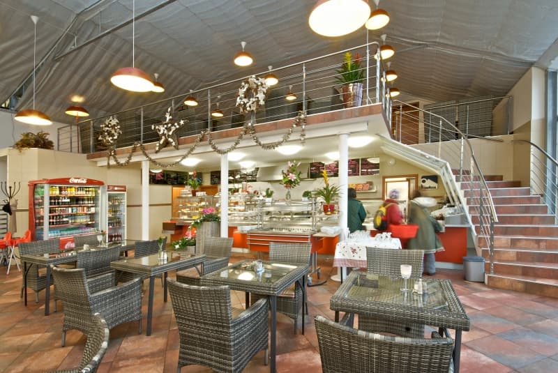 Hlavní sál restaurace s ratanovými křesly, vestavěným patrem a výdejem jídla