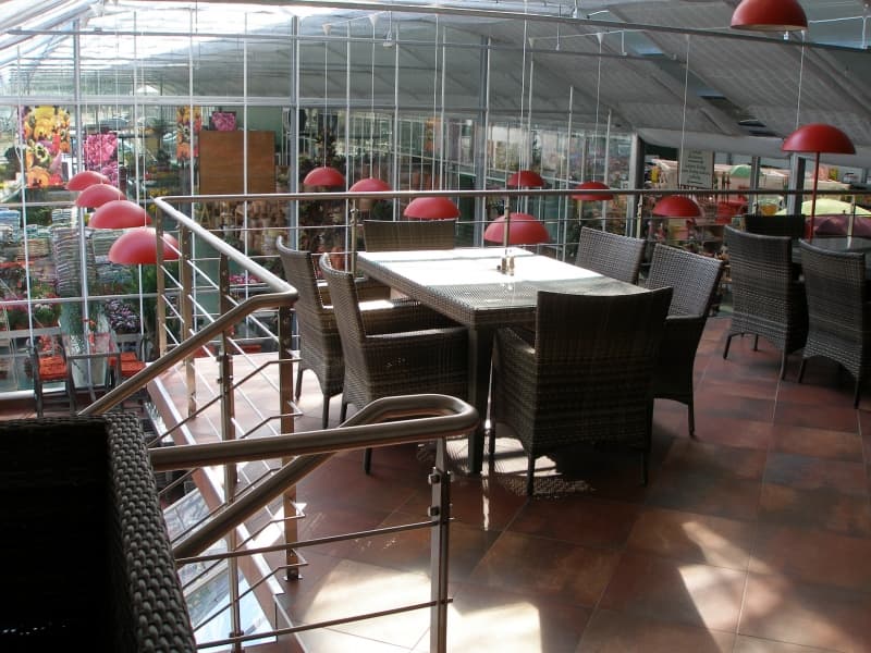 Posezení v restauraci mezi skleníky, prosklené stěny s výhledem do zahradnictví a červené lampy
